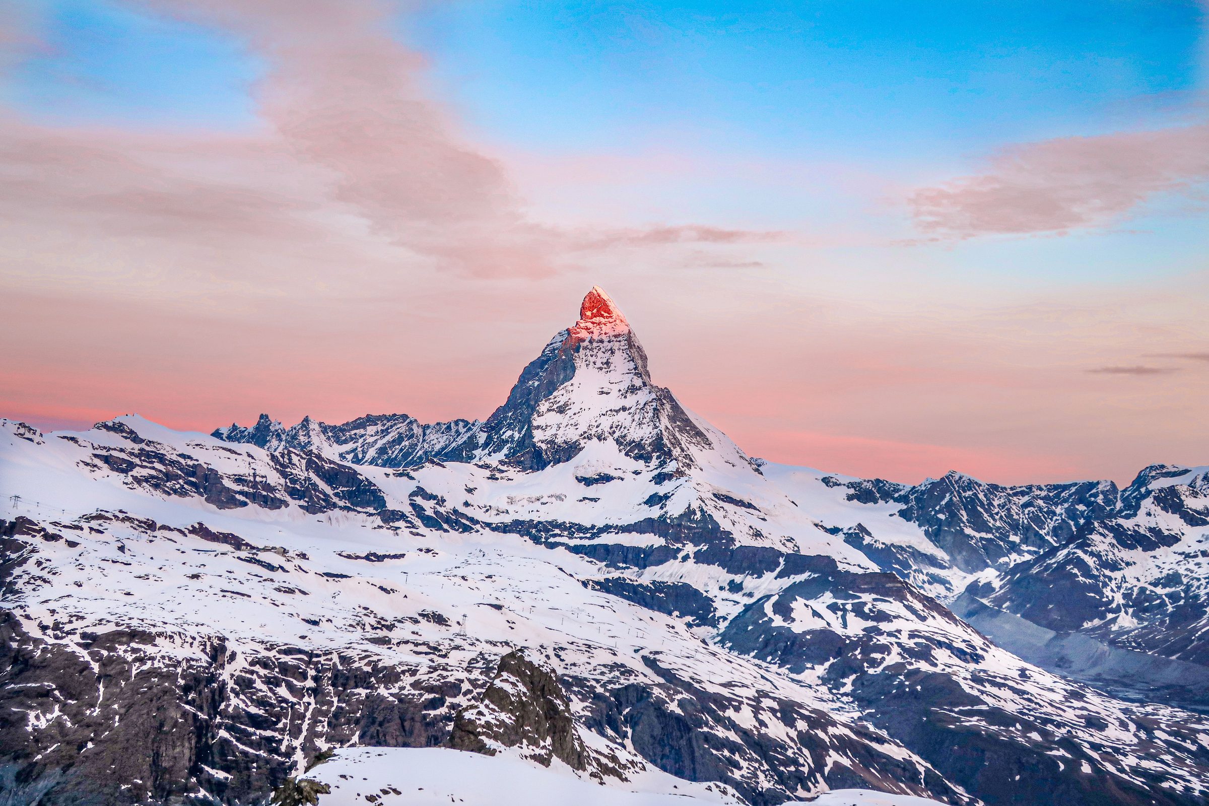 Snow-capped Alpine peaks at sunrise above a sea of clouds in the Swiss Alps